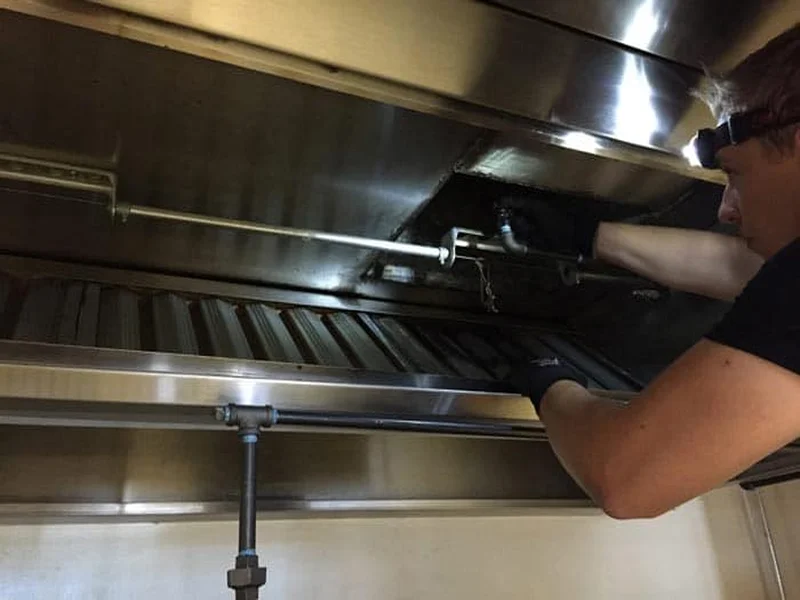 Boss Fire Protection technician inspecting fire suppression nozzles and a fusible link over a commercial cookline in Dallas-Fort Worth, TX