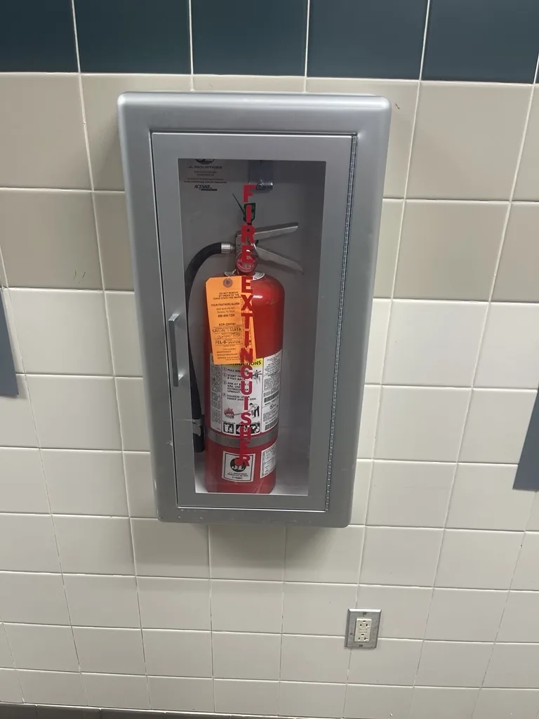 A commercial ABC fire extinguisher in a wall cabinet, inspected and tagged to NFPA 10 by Boss Fire Protection in Dallas-Fort Worth, TX