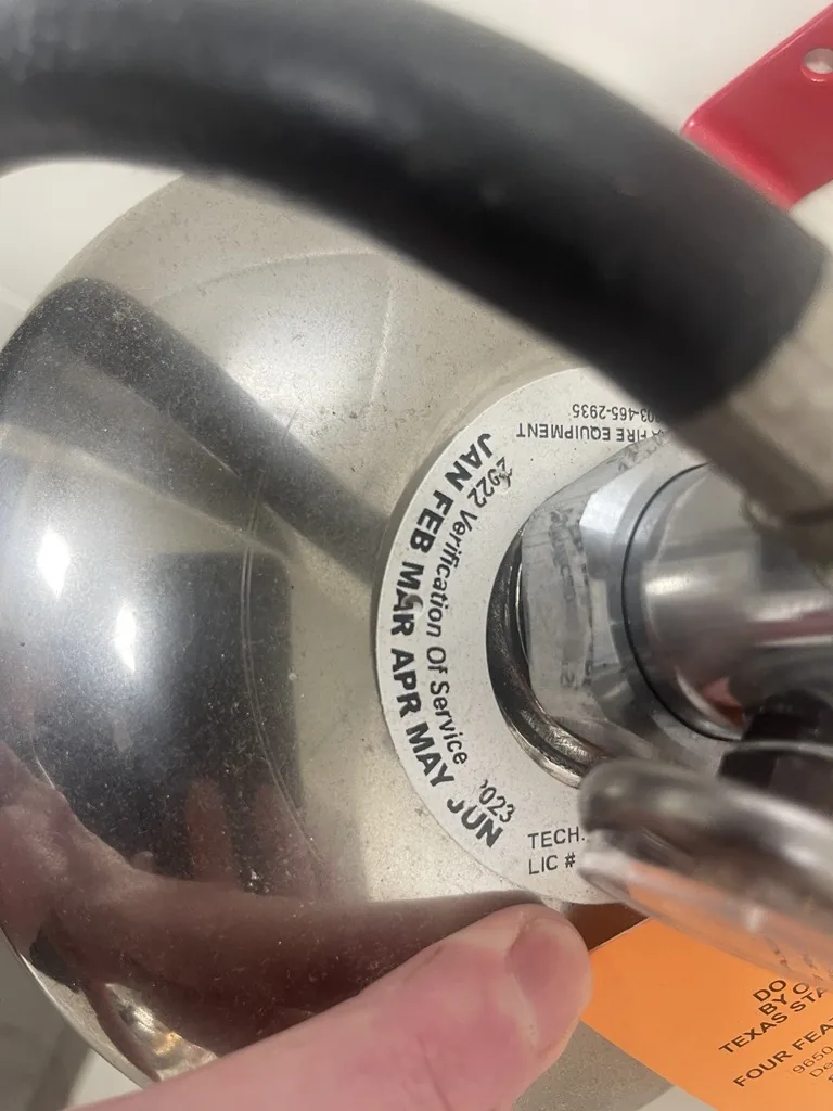 Boss Fire Protection service verification collar recording the latest service date on a commercial fire extinguisher in Dallas-Fort Worth, TX