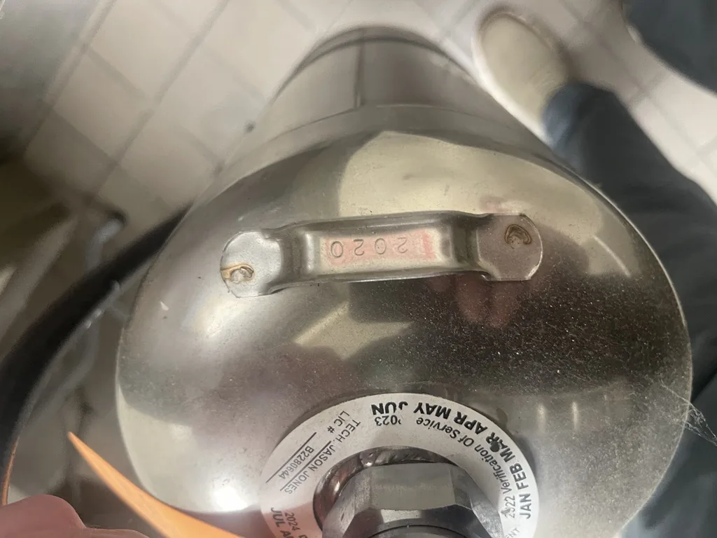 Boss Fire Protection checking the manufacture and maintenance date stamp on a commercial fire extinguisher in Dallas-Fort Worth, TX