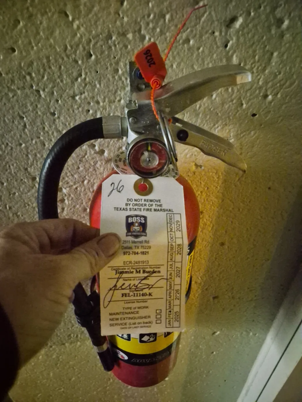 Wall-mounted commercial fire extinguisher with a current Boss Fire Protection inspection tag in Dallas-Fort Worth, TX