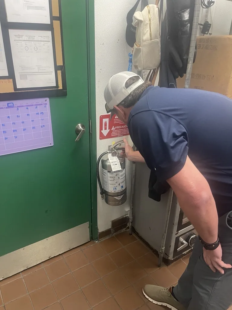 Boss Fire Protection technician inspecting a commercial K-class fire extinguisher in Dallas-Fort Worth, TX