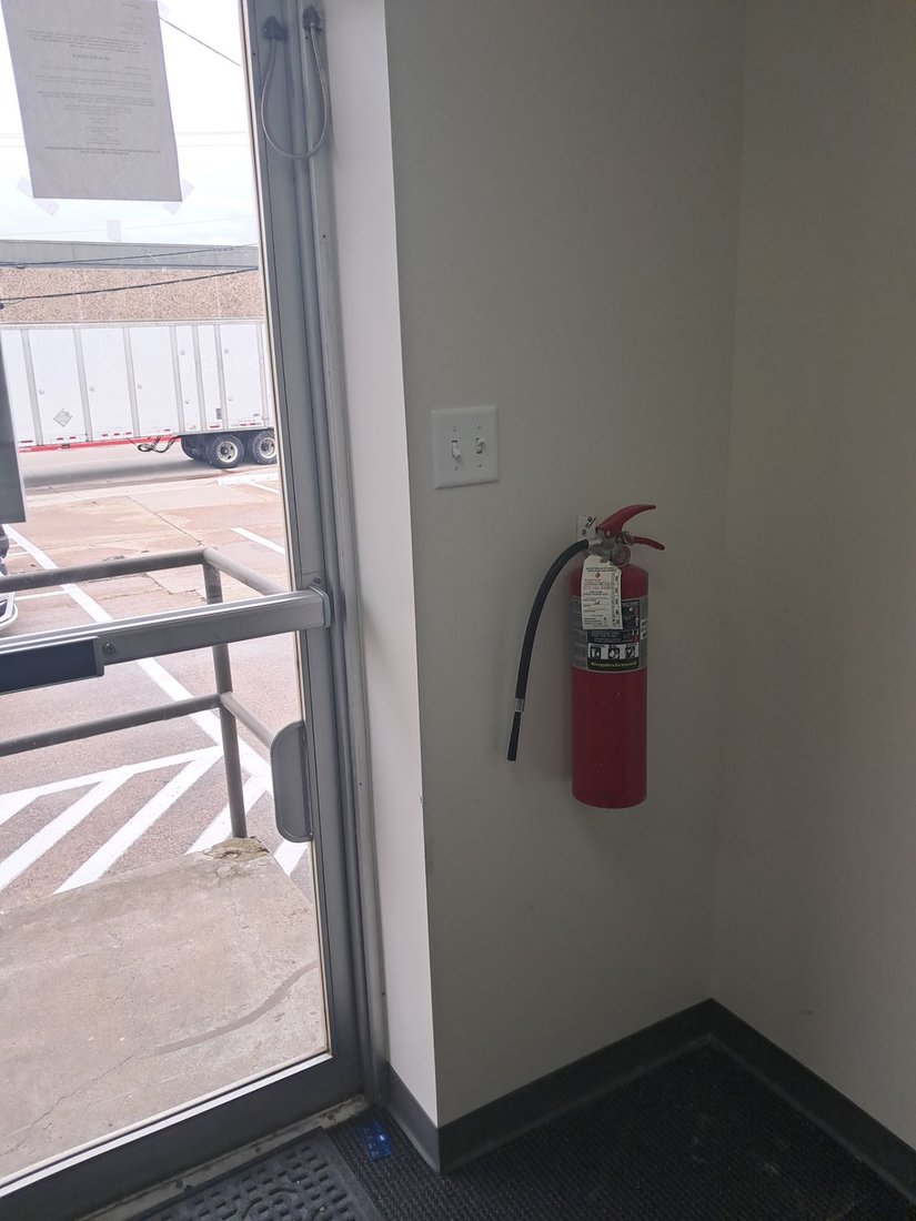 A commercial ABC fire extinguisher inspected and tagged by Boss Fire Protection at a Dallas warehouse