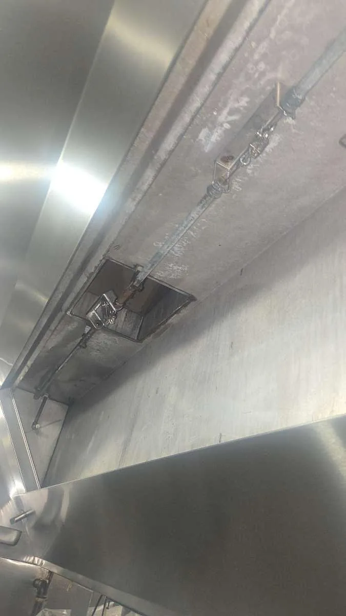 A detection line running along a commercial kitchen hood with fusible links and a nozzle at a duct collar in Dallas-Fort Worth, TX