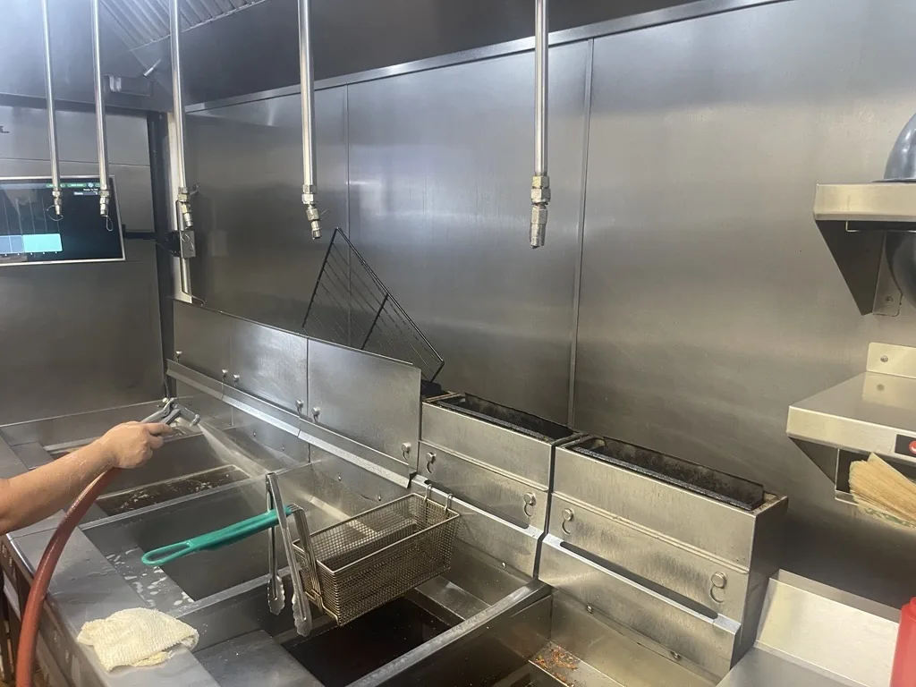 Boss Fire Protection technician checking fire suppression nozzle coverage over a commercial cookline in Dallas, TX