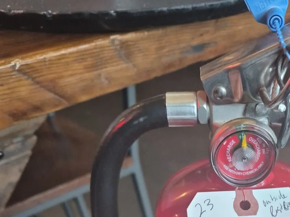 Close-up of a commercial fire extinguisher pressure gauge in the charged zone with the tamper seal and pin intact, checked by Boss Fire Protection during a Dallas-Fort Worth inspection